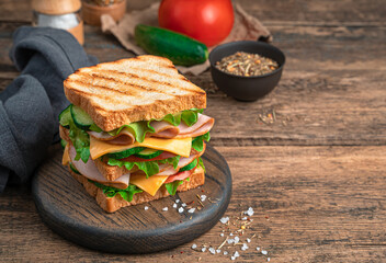 Sandwich with vegetables and ham on a wooden, brown background. Side view, copy space.