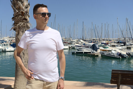 Middle aged caucasian man with hand in pocket wearing white t-shirt. Lifestyle summer background.