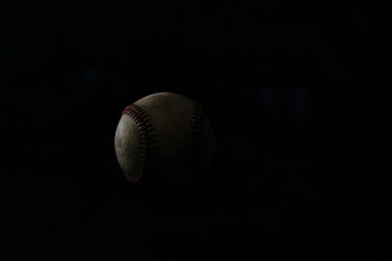 Dark moody baseball with black background of ball.