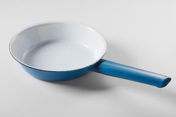 Enameled metal frying pan on white background