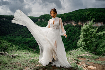 Fototapeta na wymiar woman in a wedding dress posing in the mountains. fashionable clothes for bride