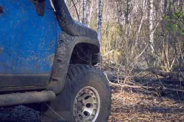 Fototapeta na wymiar Travel off-road on a forest road in a blue 4x4 car. The 4x4 SUV is all dirty