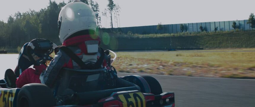 TRACKING Back view of teenager professional racer driving his go kart on a race track. Shot with 2x anamorphic lens