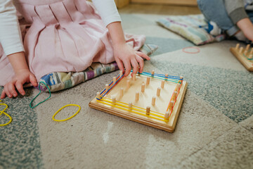 Preschool students playing with geoboard wrapping rubber bands in kindergarten