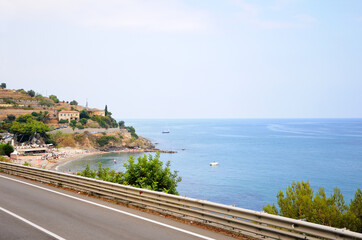 A road along the seashore. Paved road. The road along the sea from Italy to France. Cote d'Azur. The beach in a small bay in the background (Baba Beach).