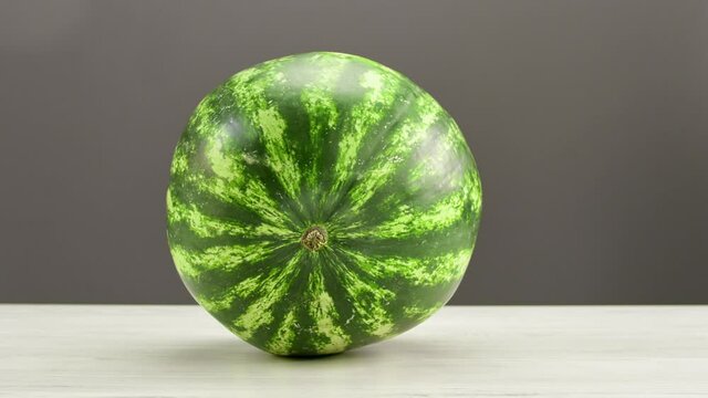 Appetizing refreshing tasty watermelon with green striped peel lying on wooden table isolated