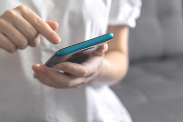 A woman using a smartphone while sitting on a couch or sofa indoors at home leisure time concept