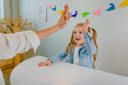 Happy Little Girl Giving High Five To Her Teacher After Good Work At Lesson