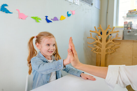 Happy Little Girl Giving High Five To Her Teacher After Good Work At Lesson