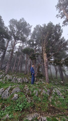 attractive man with beard in business suit stands in the mountain forest