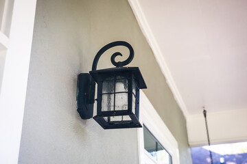 Retro black metal iron outdoor light lamp lantern hung on the exterior front entrance of a house...