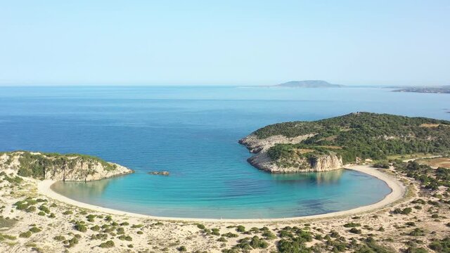 Aerial drone video of semicircular sandy beach and lagoon of Voidokilia, one of the most iconic beaches in Mediterranean sea, with crystal clear turquoise sea, Messinia, Greece