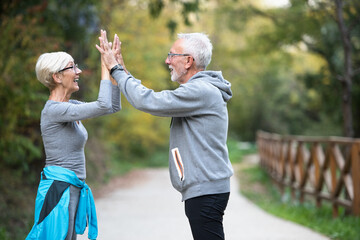 Smiling senior couple jogging in the park. Sports activities for elderly people.