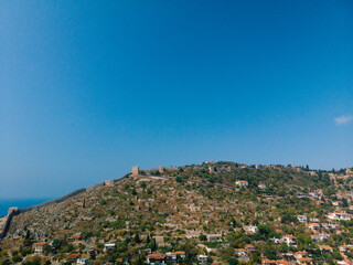 Fototapeta premium Aerial view resort city Alanya in southern coast of Turkey, Summer day. Travel and vacation. Kalesi Castle. Mountain. Ships and boats in the mediterranean