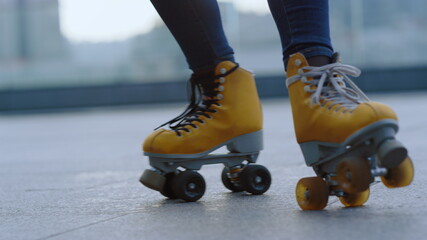 Obraz premium Unknown roller skater riding at rooftop. Woman legs dancing on rollerblades.