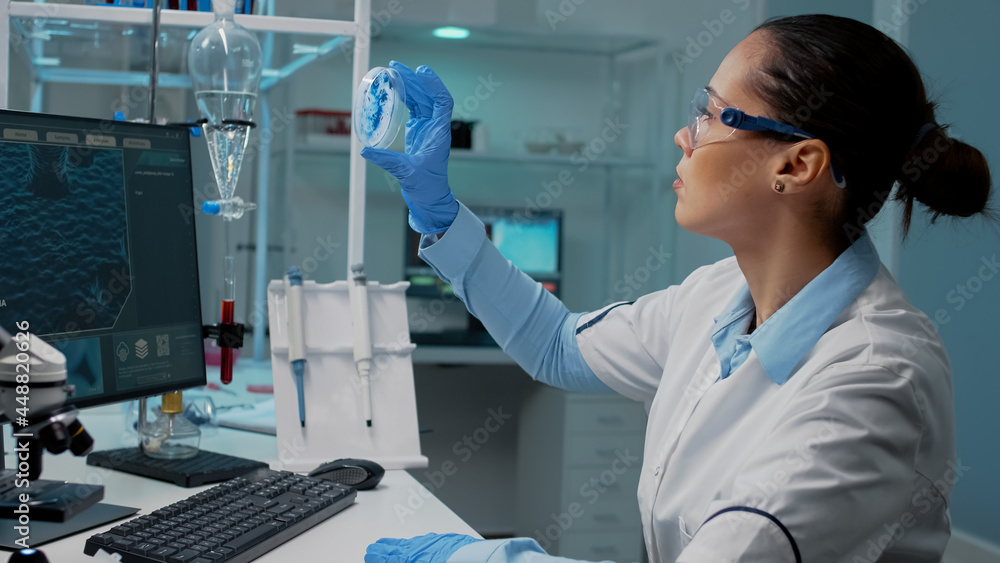 Aufkleber scientist in laboratory analyzing petri dish with liquid bacteria while typing on computer with dna 