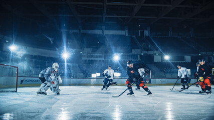 Fototapeta na wymiar Ice Hockey Arena: Professional Forward Player Breaks Defense, Prepairing to Shot Puck with Stick to Score Goal. Two Competitive Teams Play Intense Game.