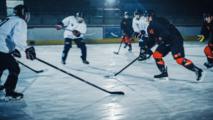 Obraz premium Ice Hockey Arena: Professional Forward Player Breaks Defense, Prepairing to Shot Puck with Stick to Score Goal. Two Competitive Teams Play Intense Game.