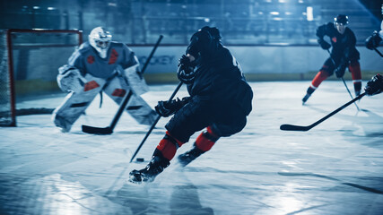 Eishockey-Arena: Professioneller Stürmer durchbricht die Verteidigung und bereitet sich darauf vor, den Puck mit Stock zu schießen, um ein Tor zu erzielen. Zwei konkurrierende Teams spielen ein intensives Spiel.