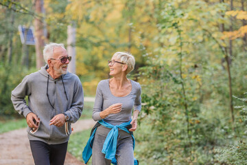 Smiling senior couple jogging in the park. Sports activities for elderly people.