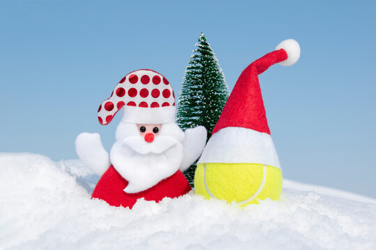 Santa Claus, Christmas tree and tennis ball in red santa hat on white snow on winter day. Merry christmas and happy New Year greeting card, creative christmas composition