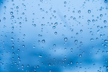 Naklejka na ściany i meble Raindrops on glass in cold colors. Soft focus cold background rainy day