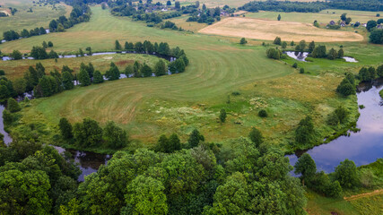 Aerial landscape of winding river in green field, top view of beautiful nature background from drone, seasonal summer landscape with copy space.