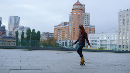 Stylish woman making steps on roller skates on street. Roller skater dancing.