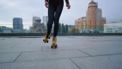 Unrecognizable woman having workout rollerblading workout at city rooftop.