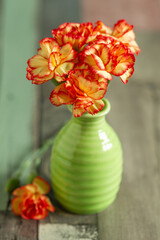 Still life image with small colorful carnations on a rustic table