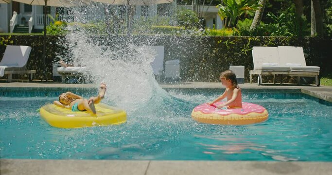 Happy diverse young family playing and jumping in the pool on summer vacation, family kids lifestyle, cinematic slow motion