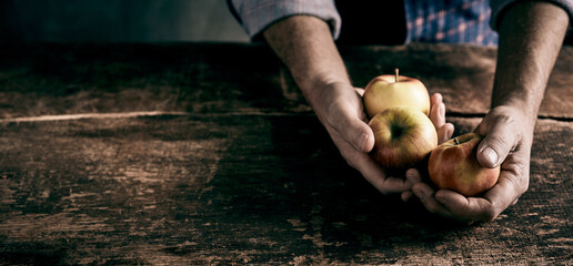 Crop man with pile of apples at table