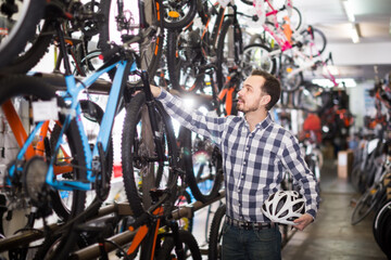 Fototapeta na wymiar active man in bicycle shop chooses for himself sports bike from a range