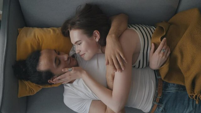 Happy couple in love lying on sofa together and relaxing at home