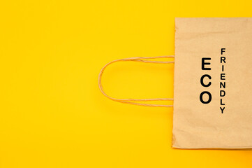 Paper recyclable eco friendly shopping bag on yellow background, top view copy space.