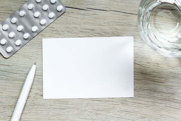 Medical capsule pills, glass water, pen , sheet of paper for noteson wooden background. Concept health, assignment