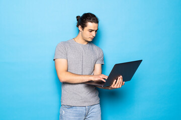 Man in casual clothes with laptop on color background