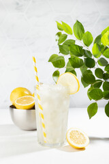 Fresh lemon tonic drink of organic lemons in misted glass with ice cubes, straw, yellow lemons,...