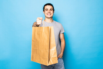 Young happy smiling handsome man holding shopping bags isolated on blue color background