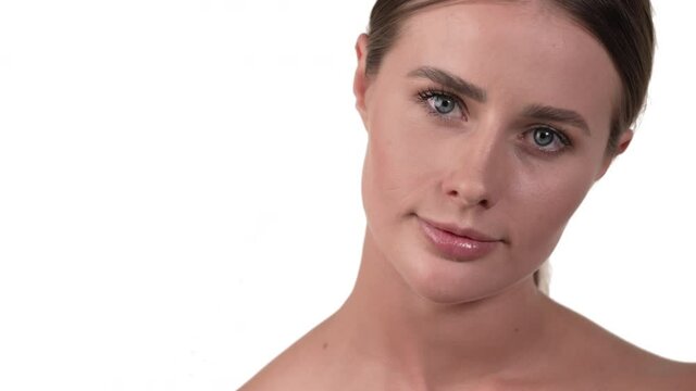Close up of woman face taking off makeup using a round cotton pad on her neck and chin. White background.