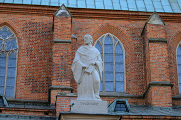 Gniezno, Poland - July 20, 2021: Sculpture of John Cantius on the eaves of the Cathedral Basilica's of the Assumption of the Blessed Virgin Mary roof