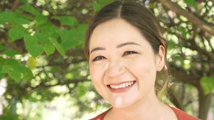 Close-up of a happily smiling girl enjoying a vacation in the countryside. Sincere positive emotions, a smile, cordiality and joy. There are reflections from the sun and a warm pleasant light on her.