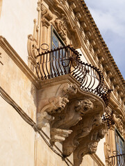 Grotesque faces with open mouth supporting a balcony of the Baroque Palazzo Beneventano, Scicli