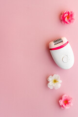 Top view of white epilator with flowers for hair removal