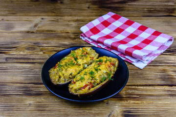 Plate with baked stuffed eggplants on a wooden table