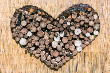 Heart formed by logs on a background made of cane. The concept of Earth Day, protection of the environment from pollution, the use of natural materials.