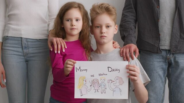 Children psychological traumas. Little brother and sister holding picture of family with selfish addicted parents