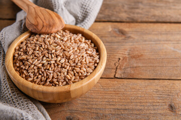 Wholegrain uncooked raw spelt farro in bowl on the wooden background, food cereal background, close up