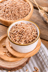 Wholegrain uncooked raw spelt farro in bowl on the wooden background, food cereal background, close up