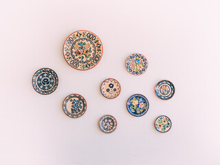 Beautifully designed ceramic colorful plates hanging on the white wall as decorations